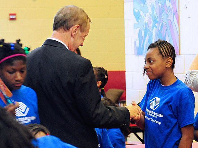 Gordon Meicher shaking hands with a girl from the Boys and Girls Club of Dane County.